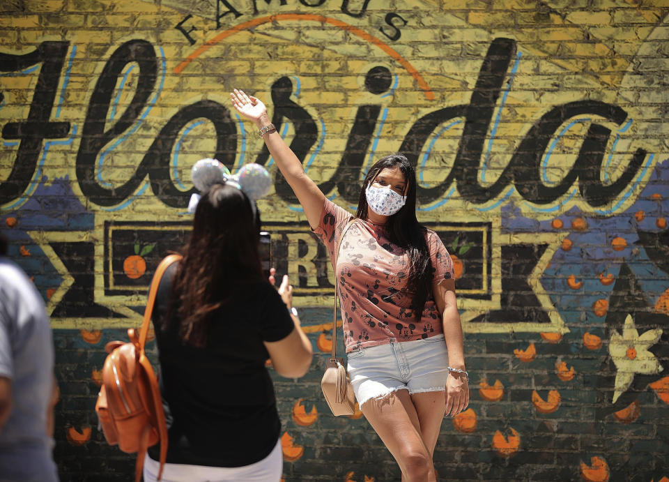 Guests take pictures at Disney Springs in Orlando, Fla., on Wednesday, May 20, 2020. Walt Disney World's sprawling shopping and dining complex is beginning the first phase of getting back to business with 44 establishments welcoming the public amid the coronavirus pandemic. (Stephen M. Dowell/Orlando Sentinel via AP)