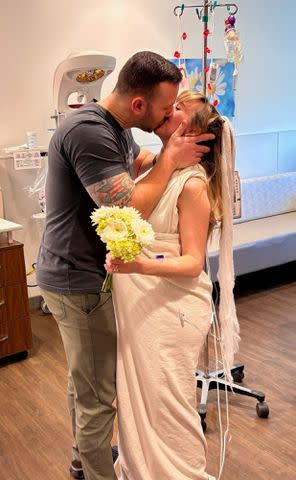 <p>Saint Luke's East Hospital</p> Brandon and Sara Perry kiss during their hospital wedding ceremony