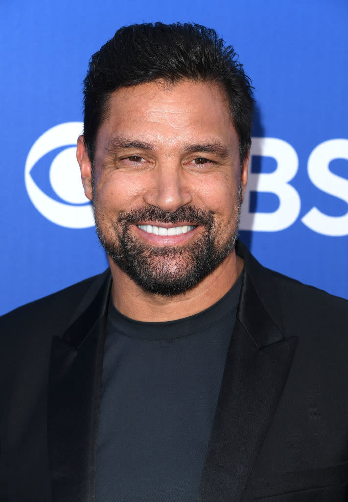 Man smiling at a CBS event, wearing a black jacket and shirt