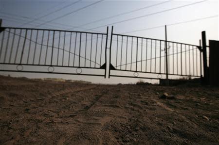 Tyre tracks are seen on a muddy road leading to a locked gate of an abandoned steel mill of Qingquan Steel Group in Qianying township, Hebei province February 18, 2014. REUTERS/Petar Kujundzic