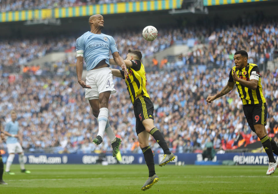 Manchester City's Vincent Kompany, left, jumps for a header with Watford's Craig Cathcart during the English FA Cup Final soccer match between Manchester City and Watford at Wembley stadium in London, Saturday, May 18, 2019. (AP Photo/Kirsty Wigglesworth)