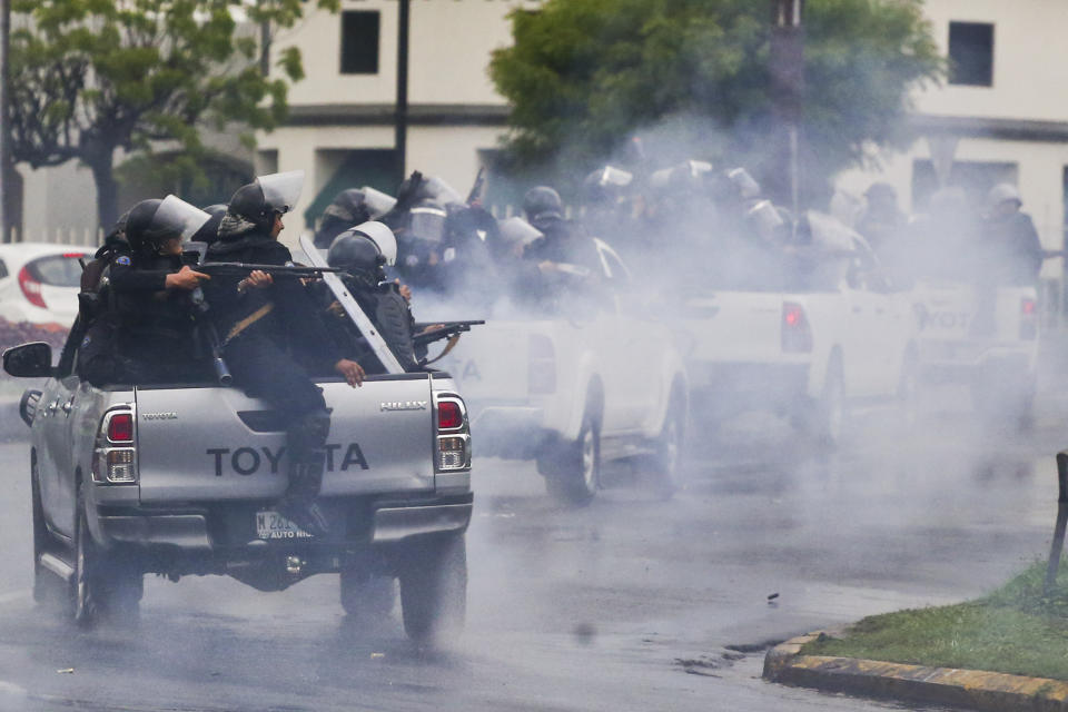 ARCHIVO - En esta foto de archivo del 28 de mayo de 2018, la policía con equipos antidisturbios montados en la parte trasera de camionetas dispara sus escopetas contra estudiantes universitarios que participan en una protesta contra el presidente de Nicaragua, Daniel Ortega, en Managua, Nicaragua. El Tesoro de los Estados Unidos anunció sanciones el viernes 22 de mayo de 2020 contra dos funcionarios nicaragüenses de alto rango por su apoyo a las medidas represivas del gobierno contra los manifestantes. (AP Foto/Esteban Felix, Archivo)