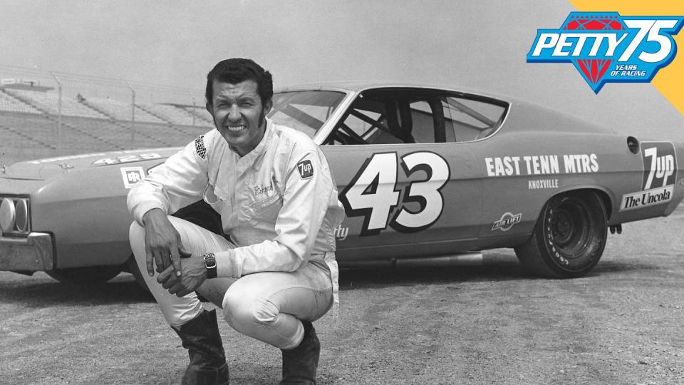 a man kneeling next to a race car