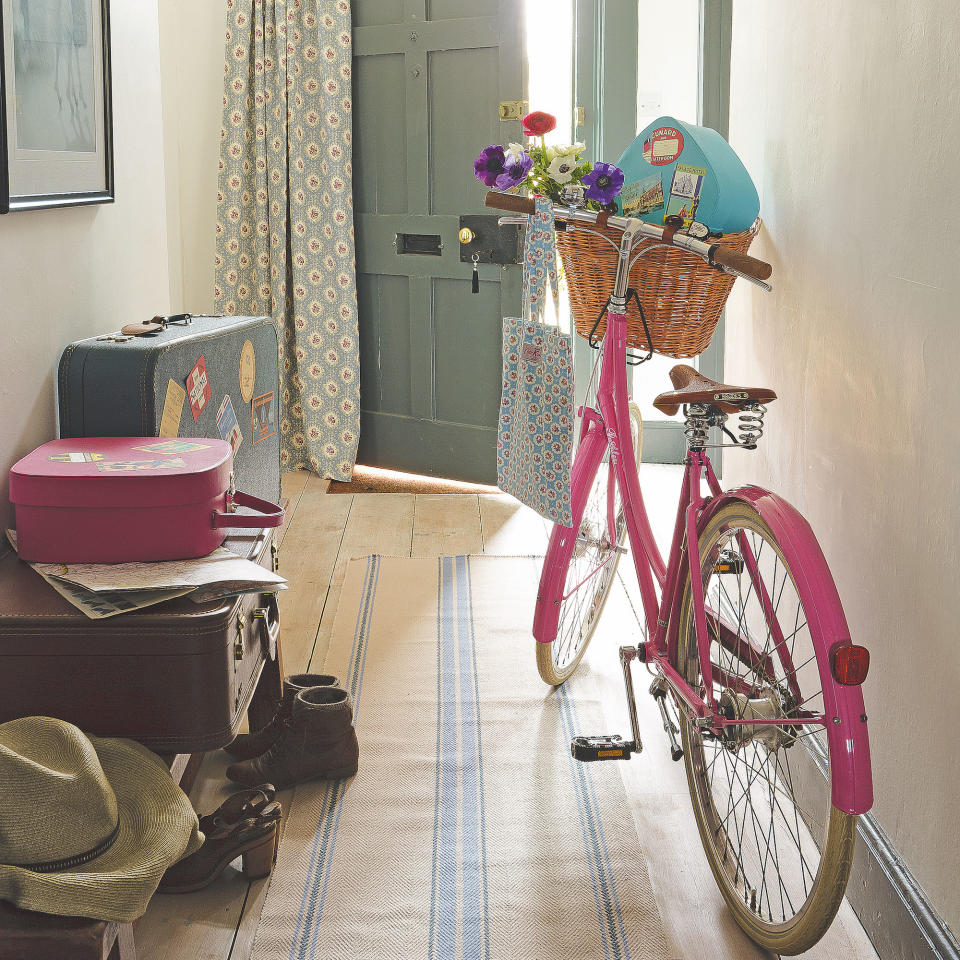 pink bike in hallway with suitcases and open door