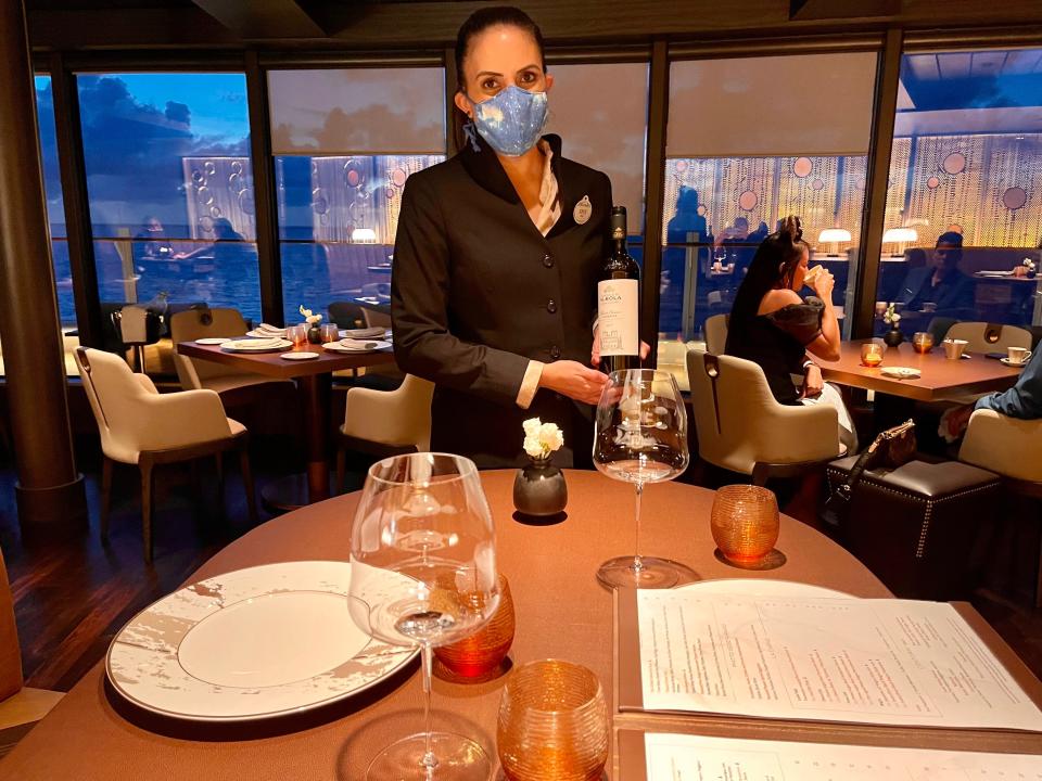 a sommelier holding bottle of wine at palo steakhouse on disney wish