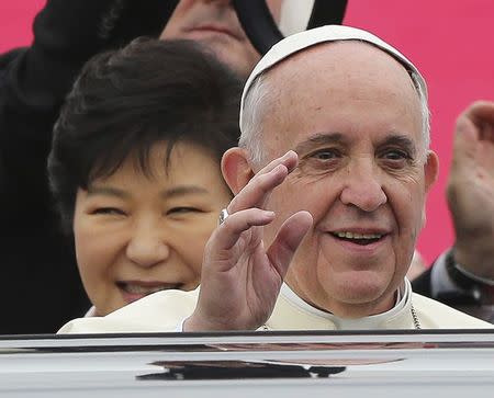 Pope Francis waves upon his arrival at Seoul Air Base, as South Korean President Park Geun-hye (L) smiles, in Seongnam, August 14, 2014. REUTERS/Ahn Young-joon/Pool