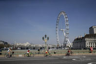 A family space themselves apart as they cycle over Westminster Bridge past the London Eye ferris wheel in London, Friday, April 10, 2020. In a statement Thursday, a spokesman at 10 Downing Street said British Prime Minister Johnson "has been moved this evening from intensive care back to the ward, where he will receive close monitoring during the early phase of his recovery." The new coronavirus causes mild or moderate symptoms for most people, but for some, especially older adults and people with existing health problems, it can cause more severe illness or death. (AP Photo/Matt Dunham)