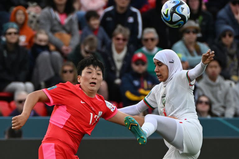 La surcoreana Park Eun-Sun lucha por la pelota con la defensora marroquí Nouhaila Benzina, que eligió jugar con hiyab