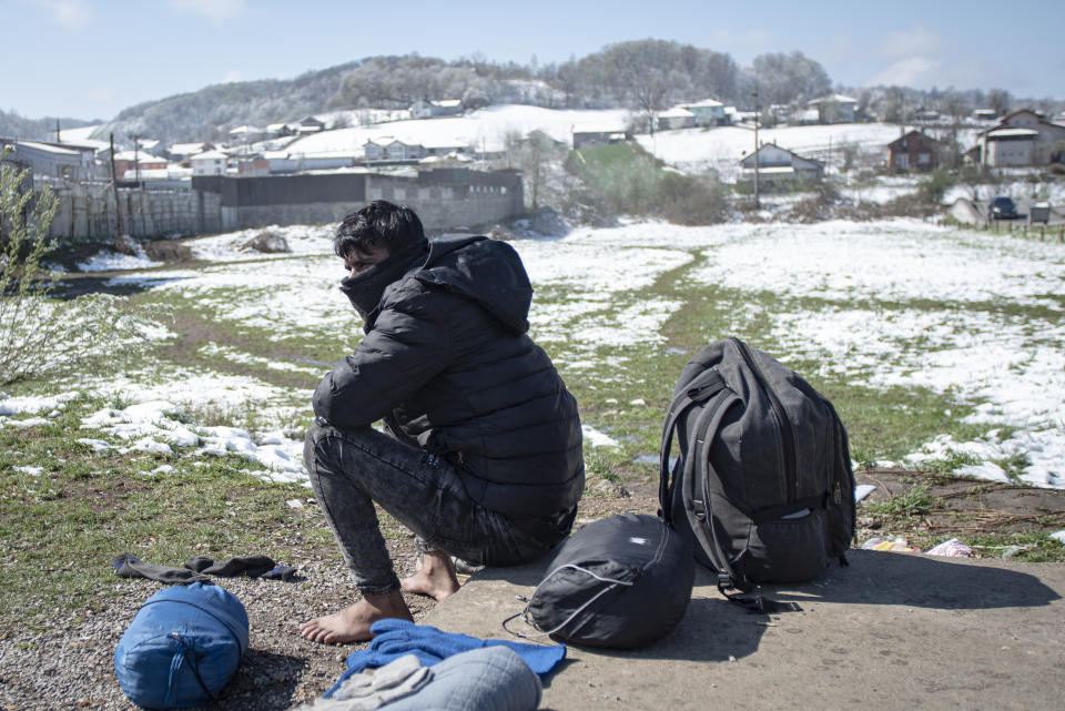 A migrant man dries his belongings outside the Miral camp, in Velika Kladusa, Bosnia, Wednesday, April 7, 2021. Bosnia is seeing a rise in coronavirus infections among migrants and refugees living in its camps, as it struggles to cope with one of the Balkans' highest COVID-19 death and infection rates among the general population.(AP Photo/Davor Midzic)