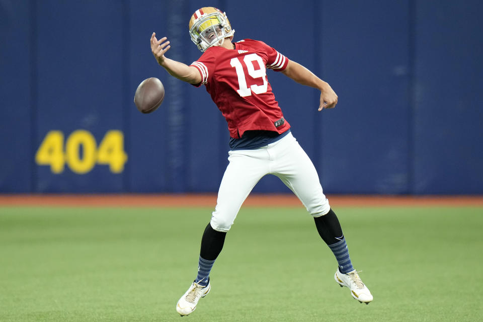 Tampa Bay Rays relief pitcher Robert Stephenson wears a San Francisco 49ers helmet and wide receiver Deebo Samuel jersey as tries to catch a pass while warming up before a baseball game against the Los Angeles Angels Thursday, Sept. 21, 2023, in St. Petersburg, Fla. (AP Photo/Chris O'Meara)