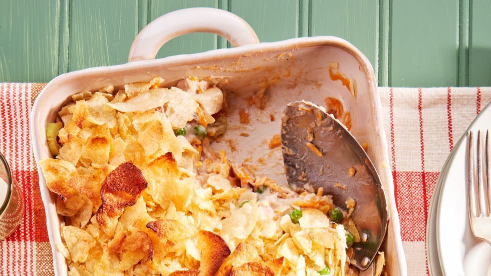 tuna noodle casserole in a cream colored rectangle baking dish with a serving spoon