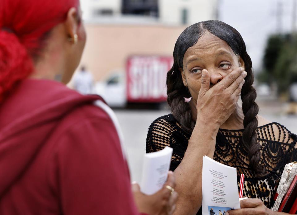 Two people talk while one holds several pamphlets and the other holds one.