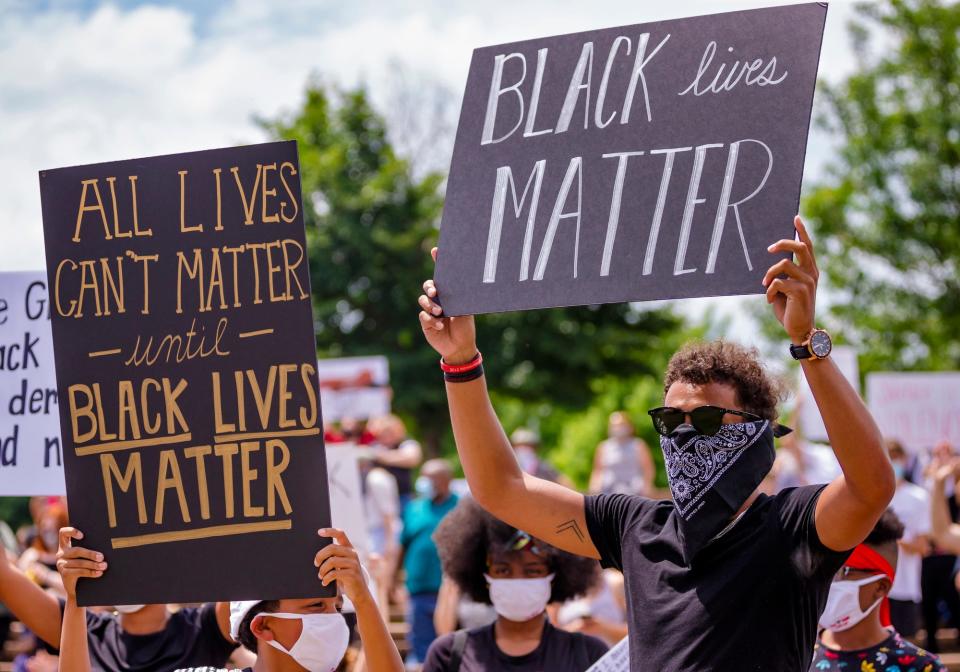 Atlanta Hawks guard Trae Young, right, gathers with protesters as they carry signs during a protest at Andrews Park on June 1, 2020, in Norman, Okla., which is Young's hometown.