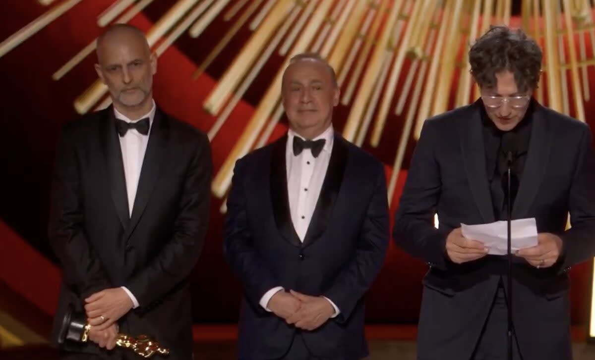 Writer-director Jonathan Glazer speaks as he accepts the Oscar for Best International Feature Film for his Holocaust film, The Zone of Interest, as producers Jim Wilson (left) and Sir Leonard Blavatnik stand behind him at the Academy Awards in Los Angeles on March 10, 2024.