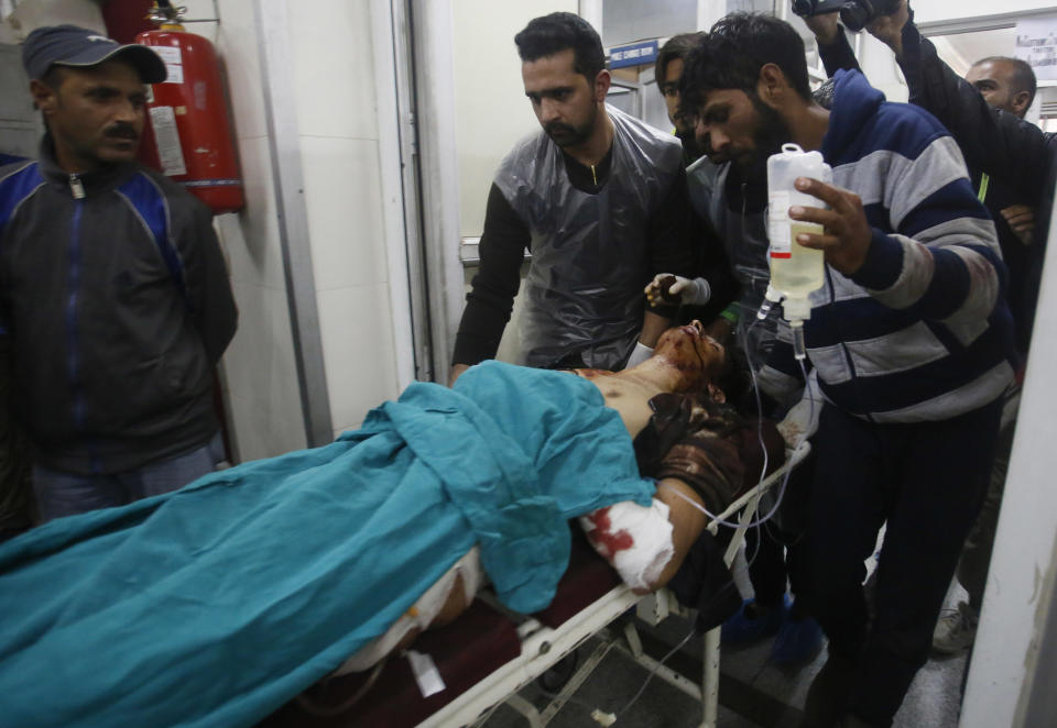 Kashmiri men take an injured civilian on a stretcher inside a hospital in Srinagar, Indian controlled Kashmir, Sunday, Oct. 21, 2018. Three suspected rebels were killed in a gun battle with Indian government forces in disputed Kashmir on Sunday, and at least three civilians were killed in an explosion at the site after the fighting was over, officials and residents said. (AP Photo/Mukhtar Khan)