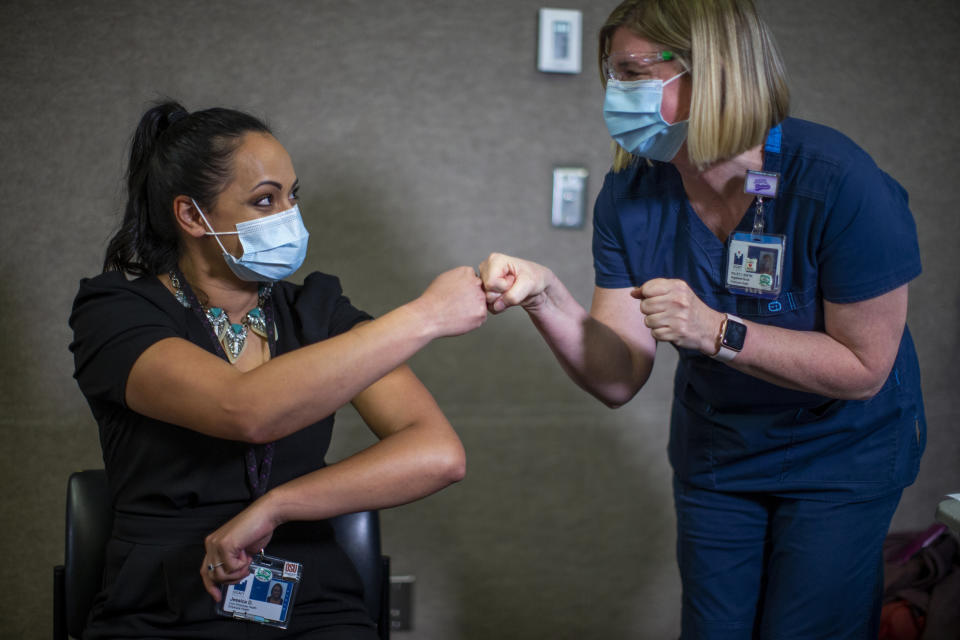 FILE - In this Dec. 16, 2020, file photo, Jessica Daniels, right, immunization program coordinator for Legacy Emanuel, first-bumps Kelley Callais after Callais administered her COVID-19 vaccination shot at at Legacy Emanuel Medical Center in Portland, Ore. Officials in Oregon learned early in the pandemic that they needed to look locally for connections to help them source increasingly scarce personal protective equipment. (Dave Killen/The Oregonian via AP)