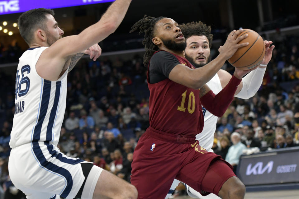 Cleveland Cavaliers guard Darius Garland (10) drives between Memphis Grizzlies guard John Konchar (46) and forward David Roddy in the second half of an NBA basketball game Thursday, Feb. 1, 2024, in Memphis, Tenn. (AP Photo/Brandon Dill)