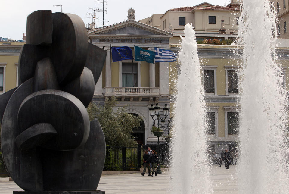 Pedestrians pass outside the National Bank of Greece headquarters in Athens, Friday, April 20, 2012. Greek banks will publish their annual reports later Friday, which are expected to include severe losses resulting from their participation in the country's massive private debt writedown earlier this year. (AP Photo/Thanassis Stavrakis)