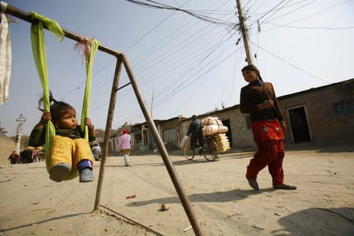 This file picture shows a 13-year-old girl looking on as a baby plays on a makeshift swing in a shantytown on the banks of the Bagmati river in Kathmandu. Life city slums is particularly hazardous in Kathmandu, where there are regular outbreaks of diarrhoea and cholera in the thousands of shanties on the banks of the river, which is used as a dump for toxic industrial and hospital waste