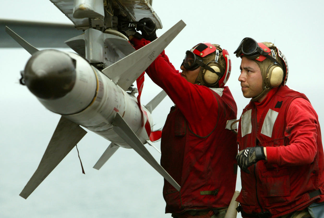 Two aviation ordnancemen load an AGM-88 HARM air-to-surface missile.