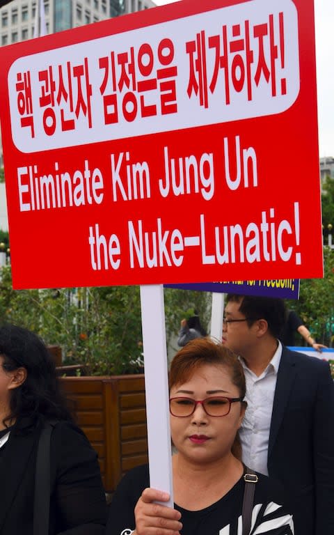 Former North Korean defectors and protestors hold placards during an anti-North Korea rally outside South Korean government complex in Seoul - Credit: YEON-JE/AFP/Getty Images