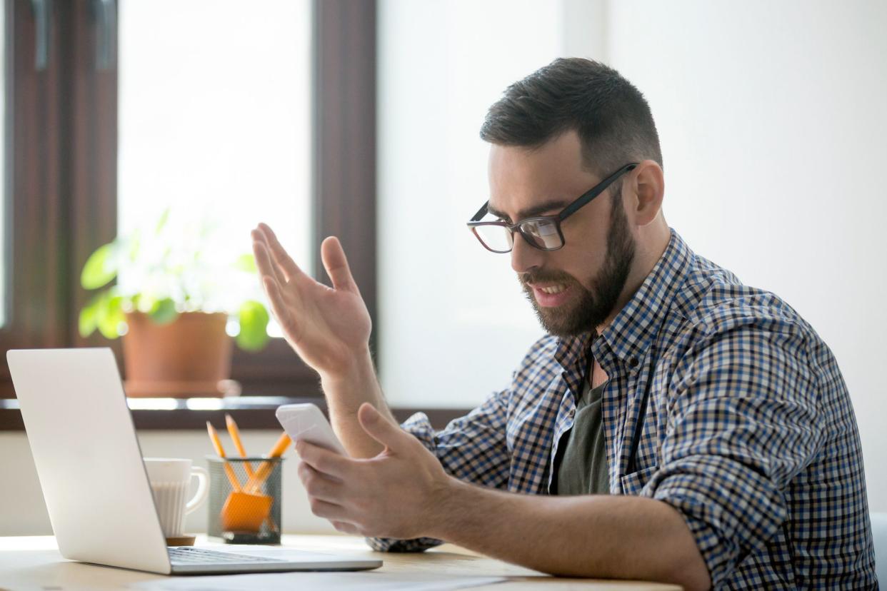 man looking at phone with indignant expression