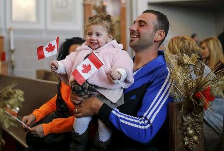 Syrian refugees Kevork Jamgochian holds his daughter Madlin at the St. Mary Armenian Apostolic Church during a welcome serivice at the Armenian Community Centre of Toronto in Toronto, December 11, 2015. REUTERS/Mark Blinch