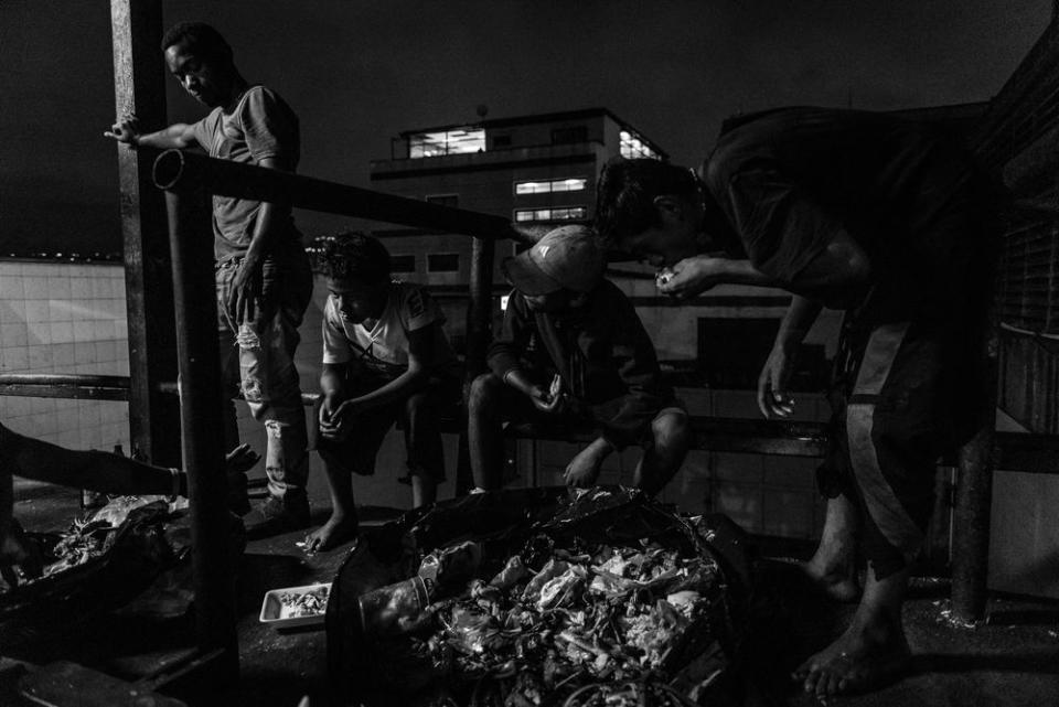 Children scavenge for food in the back alley of a large shopping center.