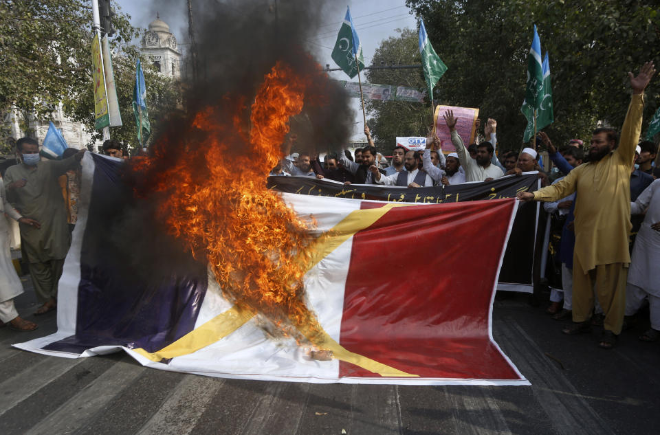 FILE - In this Oct.30, 2020 file photo, supporters of religious group burn a representation of a French flag during a rally against French President Emmanuel Macron and republishing of caricatures of the Prophet Muhammad they deem blasphemous, in Lahore, Pakistan. A spotlight of suspicion encircled Muslims again even before the latest acts of extremist violence, including two beheadings. French President Emmanuel Macron has forged ahead with a plan to rid Islam in France of extremists, part a project he labels "separatism," a term that makes some Muslims wince. (AP Photo/K.M. Chaudary, File)