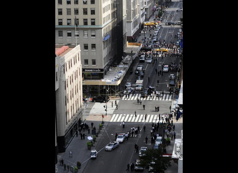 Police surround a sheet covered body, lowser left, on a Fifth Avenue sidewalk as they investigate a multiple shooting outside the Empire State Building, Friday, Aug. 24, 2012, in New York. At least four people were shot on Friday morning and the gunman was dead, New York City officials said. A witness said the gunman was firing indiscriminately. Police said as many as 10 people were injured, but it is unclear how many were hit by bullets. A law enforcement official said the shooting was related to a workplace dispute. The official spoke on condition of anonymity because the investigation was ongoing. (AP Photo/ Louis Lanzano)