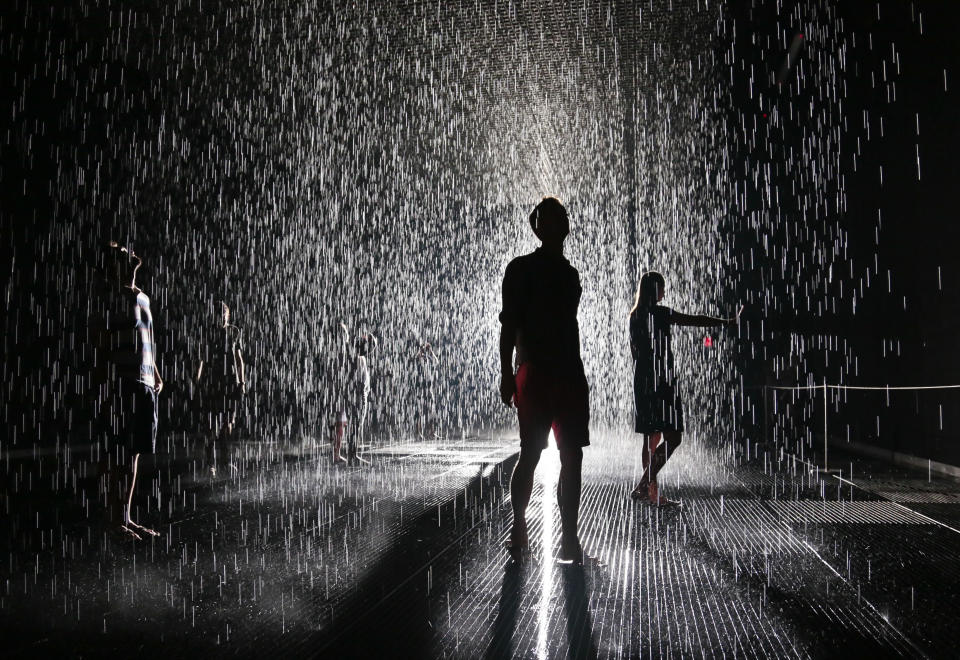 FILE - In this July 19, 2013 file photo, visitors pace through an environment of falling water at the Random International’s "Rain Room" at the Museum of Modern Art (MoMA) in New York. In New York, lines were hours-long at the Museum of Modern Art for the chance to experience the Rain Room. Falling rain paused when a human body approached. Watch next year for Oculus Rift, a virtual reality headset that makes players feel like they're inside the game screen. (AP Photo/Bebeto Matthews, File)