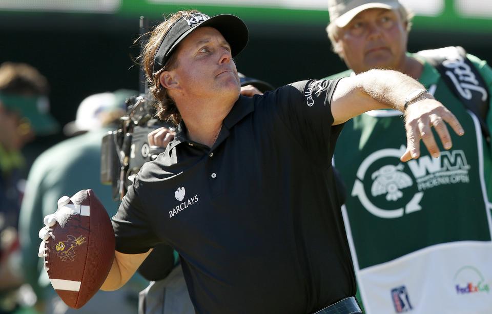 Phil Mickelson throws a football into the stands from the 16th tee during the third round of the Phoenix Open golf tournament Saturday, Feb. 1, 2014, in Scottsdale, Ariz. (AP Photo/Ross D. Franklin)