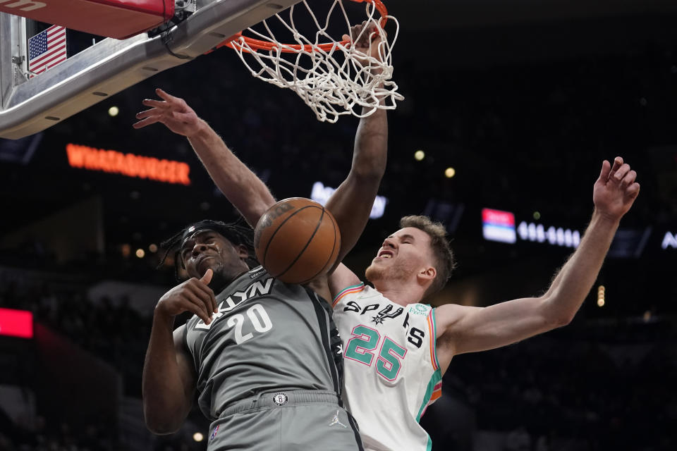 Brooklyn Nets center Day'Ron Sharpe (20) dunks next to San Antonio Spurs center Jakob Poeltl (25) during the first half of an NBA basketball game Friday, Jan. 21, 2022, in San Antonio. (AP Photo/Eric Gay)