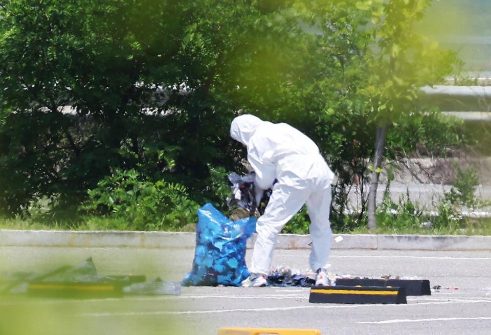 An officer wearing protective gear collects the trash from a balloon presumably sent by North Korea (AP)