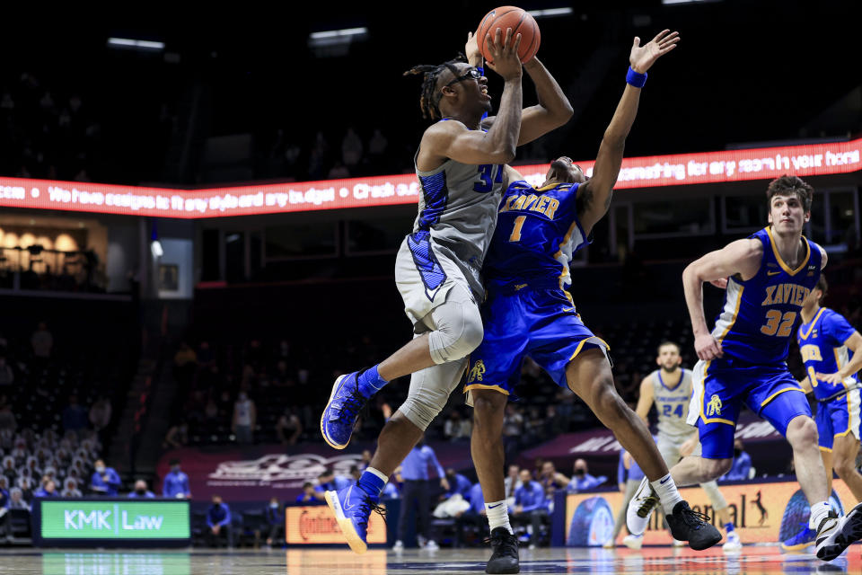 Creighton guard Denzel Mahoney, left, drives to the basket and is fouled by Xavier guard Paul Scruggs during the second half of an NCAA college basketball game Saturday, Feb. 27, 2021, in Cincinnati. Xavier won 77-69. (AP Photo/Aaron Doster)