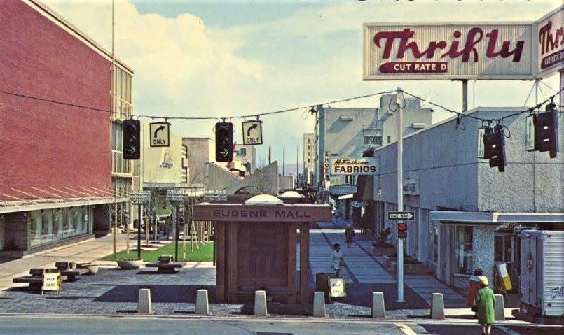 Color postcard of Eugene Mall. Taken from Charnelton intersection with Broadway (Ninth Avenue) looking east up Broadway. The Bon Marche Store on left, Eugene Mall bus stop in center and Thrifty Drug Store on the right.