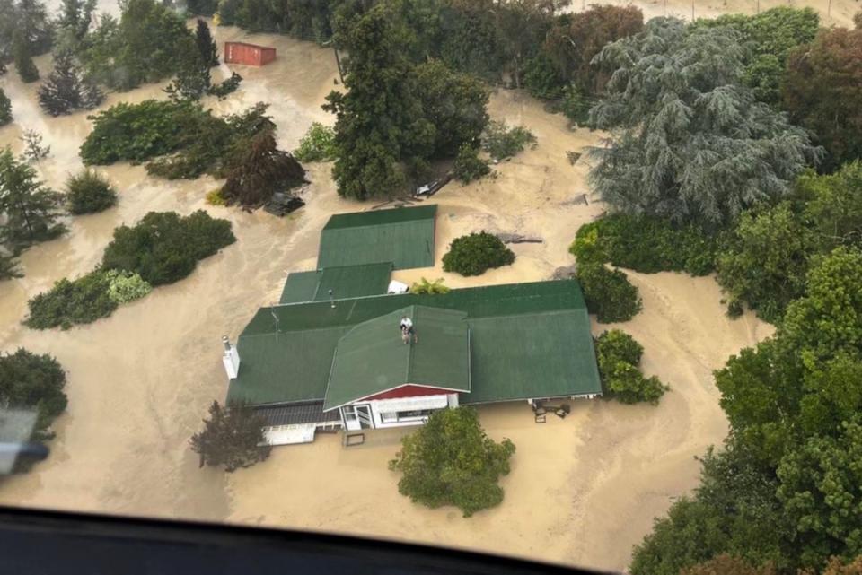 Stranded people preparing to be air-lifted from their rooftop by a military helicopter in the Esk Valley, near the North Island city of Napier (New Zealand Defence Force/AFP)