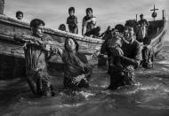 <p>Rohingya refugees flee into Bangladesh: A Rohingya refugee is helped from a boat as she arrives at Shah Porir Dwip, near Cox’s Bazar, Bangladesh, Oct. 1, 2017.<br>Attacks on the villages of Rohingya Muslims in Myanmar, and the burning of their homes, led to hundreds of thousands of refugees fleeing into Bangladesh on foot or by boat. Many died in the attempt. According to UNICEF, more than half of those fleeing were children. In Bangladesh, refugees were housed in existing camps and makeshift settlements. Conditions became critical; basic services came under severe pressure and, according to a Médecins Sans Frontières physician based there, most people lacked clean water, shelter and sanitation, bringing the threat of disease. (Photo: Kevin Frayer/Getty Images) </p>