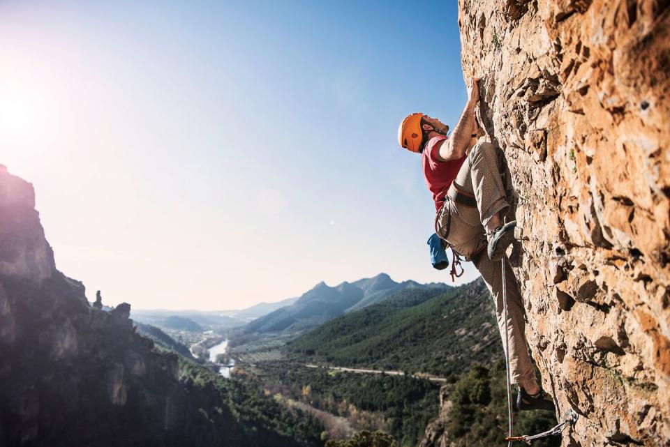 Low Angle View Of Man Rock Climbing Against Sky