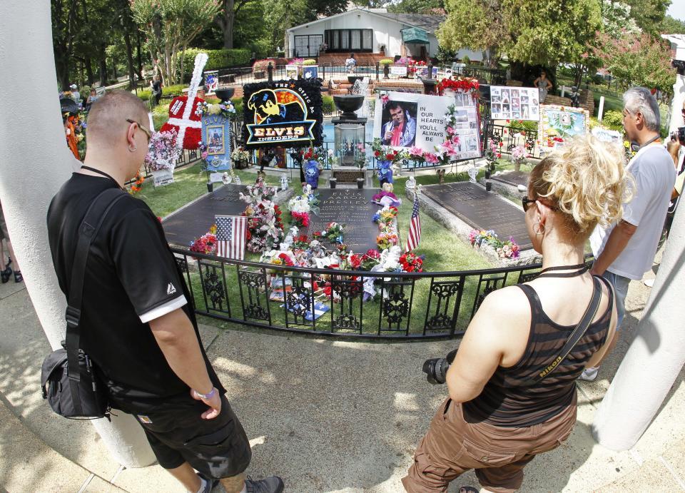 FILE -- This Aug. 2010 photo shows tourists viewing the grave of Elvis Presley at Graceland, Presley's home in Memphis, Tenn. Graceland opened for tours on June 7, 1982. They sold out all 3,024 tickets on the first day and didn't look back, forever changing the Memphis tourist landscape while keeping Elvis and his legend alive.(AP Photo/Mark Humphrey)