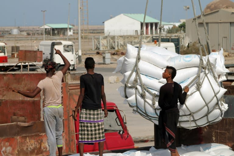 Workers unload bags from a UN World Food Programme ship docked in Yemen's devastated port city of Aden