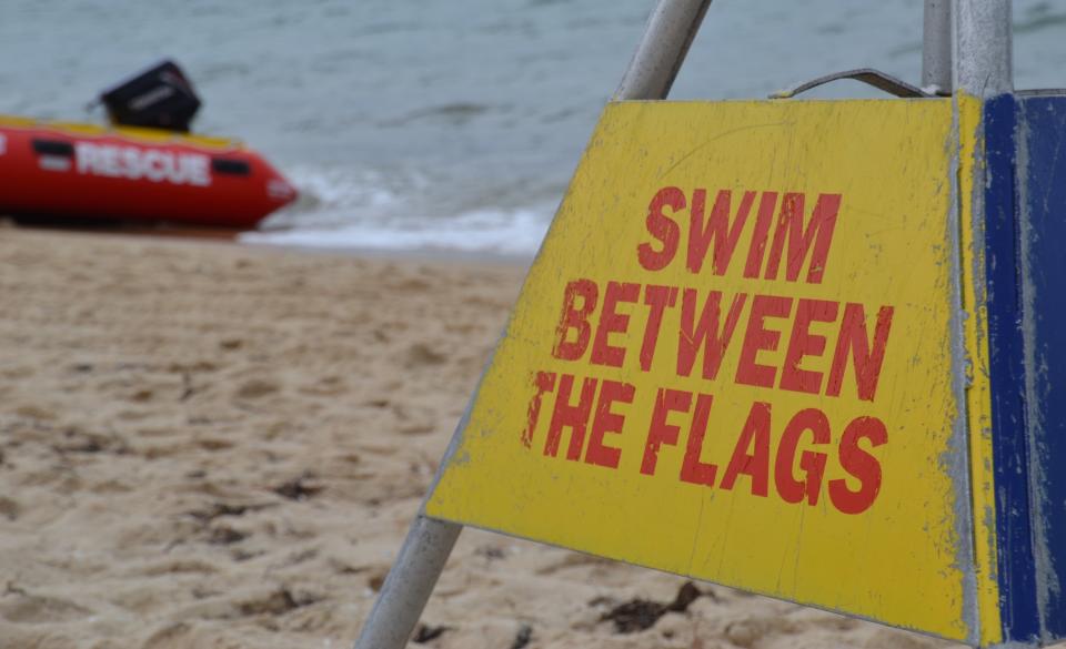 sign that reads, "Swim between the flags," on a beach in Australia