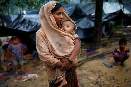 A Rohingya refugee woman wraps her child with a scarf as it drizzles in Cox's Bazar, Bangladesh, September 17, 2017. REUTERS/Mohammad Ponir Hossain