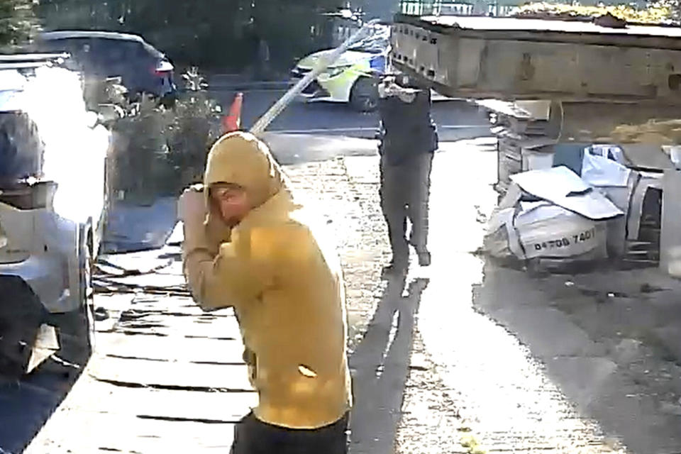 Handout footage from a doorbell camera of police officers tasering a sword-wielding man in Hainault, north east London, after a 14-year-old boy died after being stabbed following an attack on members of the public and two police officers, Tuesday April 30, 2024. (PA via AP)