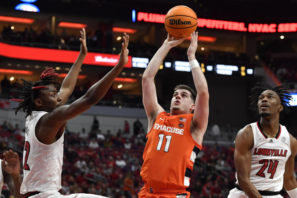 Syracuse guard Joseph Girard III (11) shoots over Louisville forward Kamari Lands (22), left, and forward Jae' Lyn Withers (24) during the first half of an NCAA college basketball game in Louisville, Ky., Tuesday, Jan. 3, 2023. (AP Photo/Timothy D. Easley)