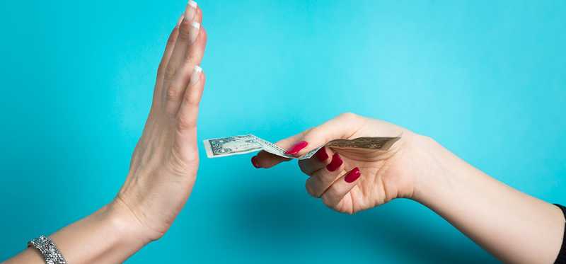 A hand is held up to prevent a woman from handing it cash.