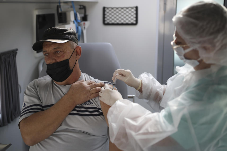 A medical staff member administers a dose of Russia's Sputnik V COVID-19 vaccine inside a mobile vaccination center in Krymsk, Krasnodar region, Russia, Friday, Oct. 29, 2021. Russia has recorded another record of daily coronavirus deaths even as authorities hope to stem contagion by keeping most people off work. Authorities have blamed soaring infections and deaths on Russia's lagging pace of vaccinations. About 51 million Russians — just over a third of the country's nearly 146 million people — were fully vaccinated as of Friday. (AP Photo/Vitaly Timkiv)