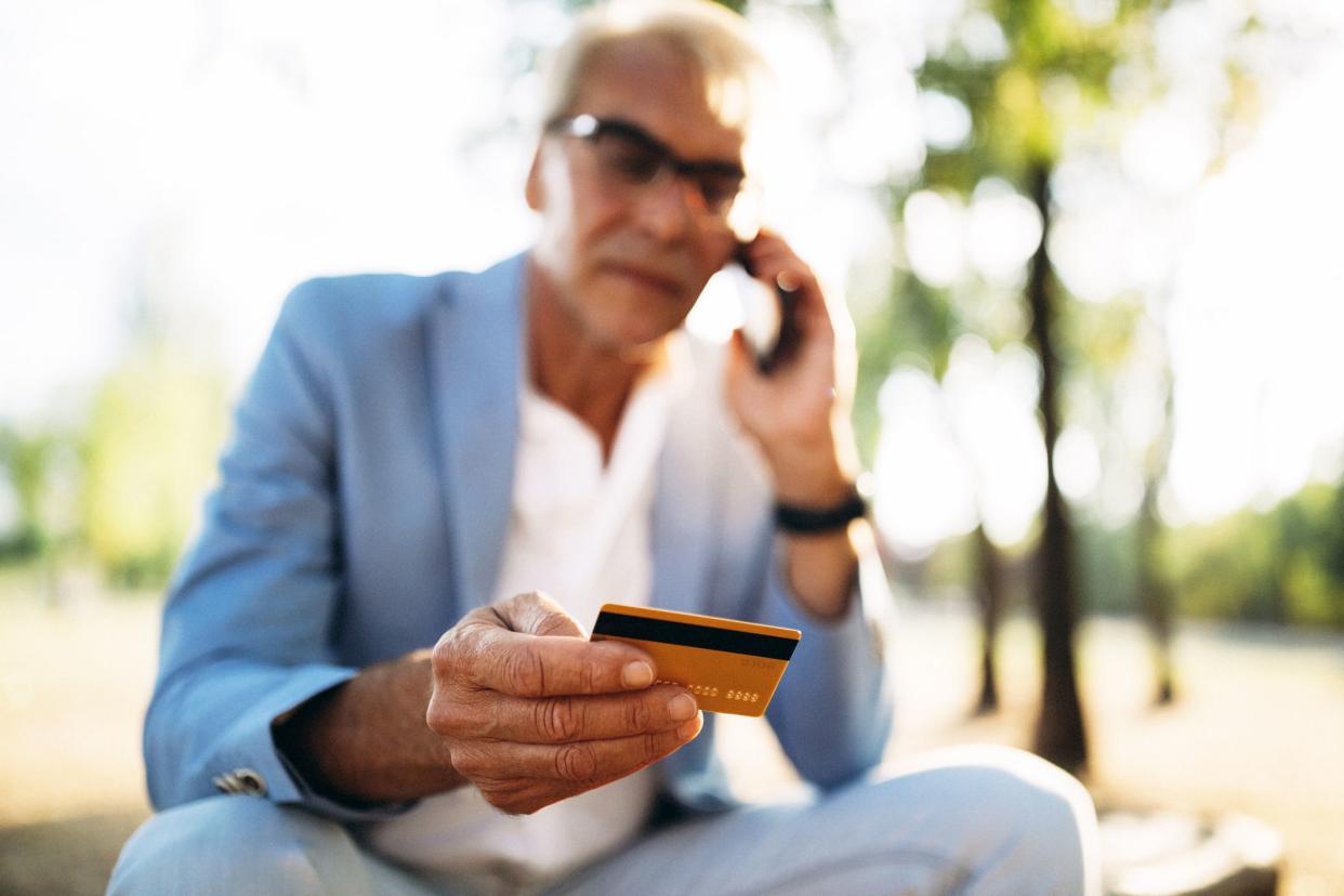 man on phone looking at credit card