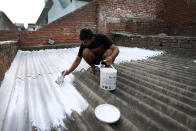 A person paints his rooftop with cool white reflective paint which brings down indoor temperature in summer, in Ahmedabad, India, Monday, May 23, 2022. The intense heat wave sweeping through South Asia was made more likely due to climate change and it is a sign of things to come. An analysis by international scientists said that this heat wave was made 30-times more likely because of climate change, and future warming would make heat waves more common and hotter in the future. (AP Photo/Ajit Solanki)