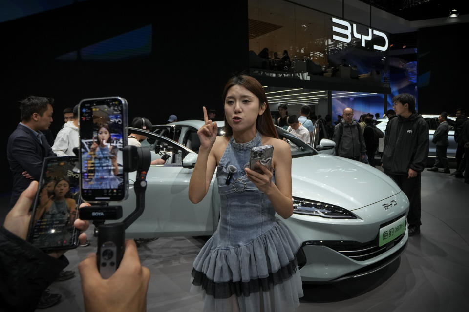 A model performs a live-streaming near a BYD Sea Leopard DM-i car model during the Auto China 2024 in Beijing, Sunday, April 28, 2024. Global automakers and EV startups unveiled new models and concept cars at China's largest auto show, with a focus on the nation's transformation into a major market and production base for digitally connected, new-energy vehicles. (AP Photo/Andy Wong)